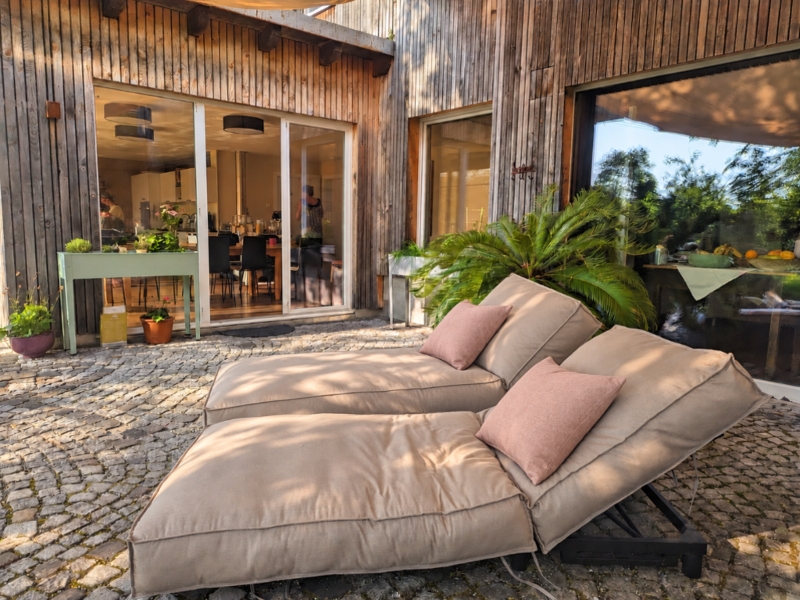 Terrasse mit 2 Liegen und Pflanzen.