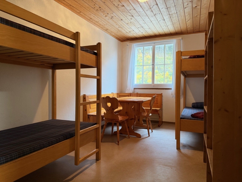 A room with several bunk beds and a corner bench.