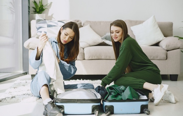 Frauen packen ihr gepaeck im Hotel aus