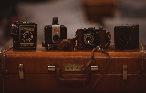 Vier verschiedenfarbige Kameras auf braunem Koffer